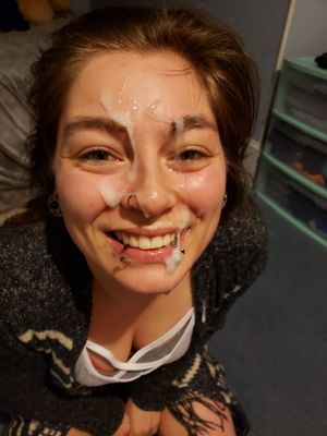 Cute clothed brunette with a smile and cum all over her face