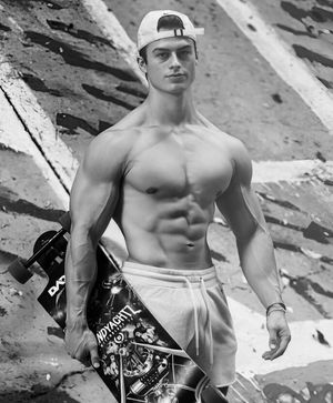 Chico musculoso joven caliente sosteniendo un patín