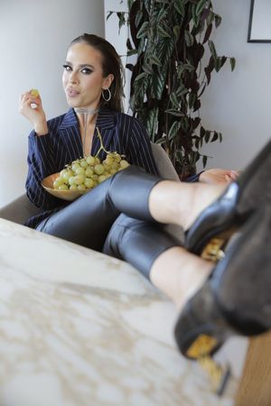 Brunette beauty in a classy outfit and high heels relaxing while looking hot