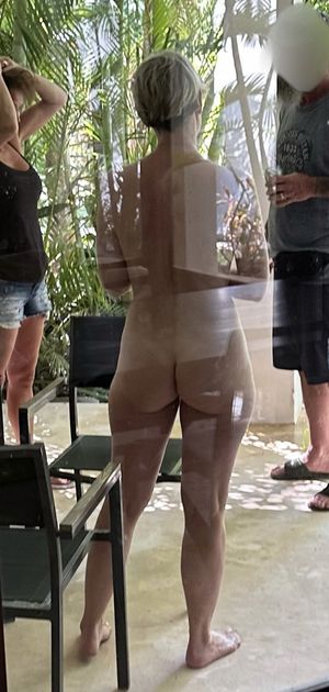 Hot milf completely nude talking to clothed man and woman. We see her sexy ass and thighs from behind glass patio door