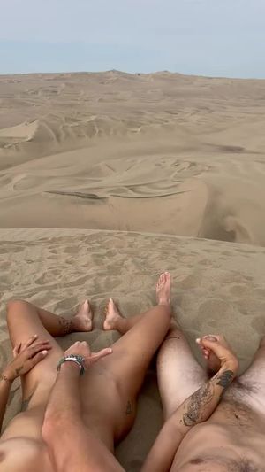 Couple masturbating in the sand