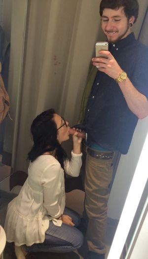Amateur mirror-shot of a brunette with glasses sucking cock in a dressing room