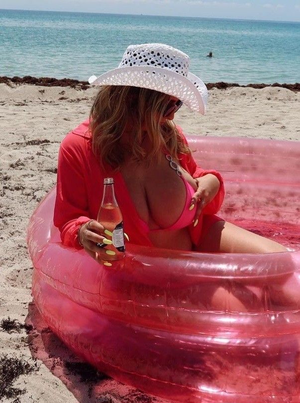 Jolie in tube holding boob and beer