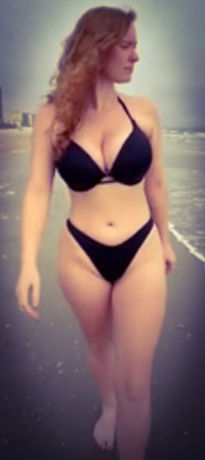 curvy brunette in black bikini walking on beach