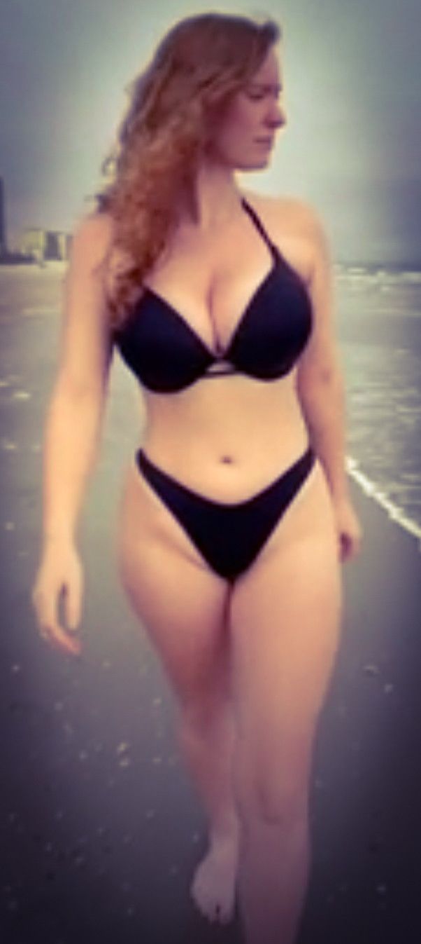 curvy brunette in black bikini walking on beach