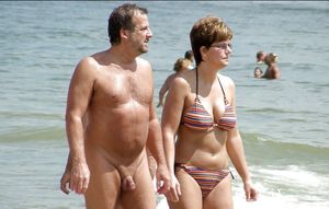 Naked man clothed woman on a beach