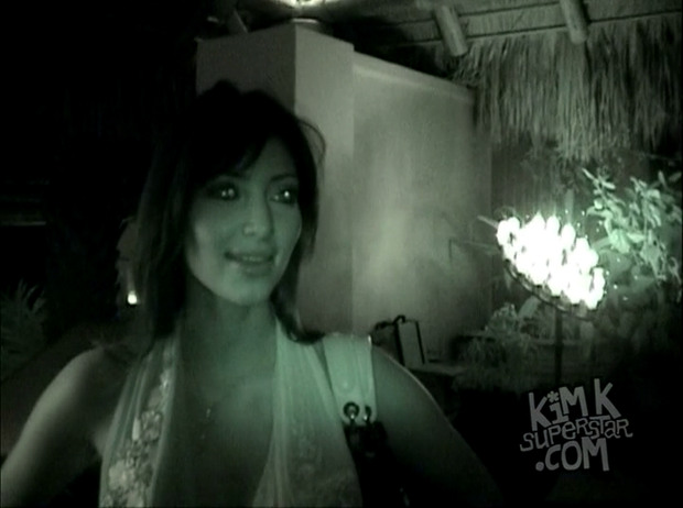 Kim K under some green night vision effect waits for a cab.