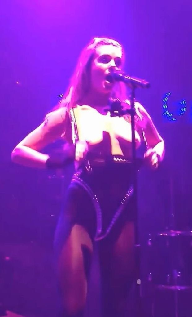 Tove Lo shows boobs while singing at concert.